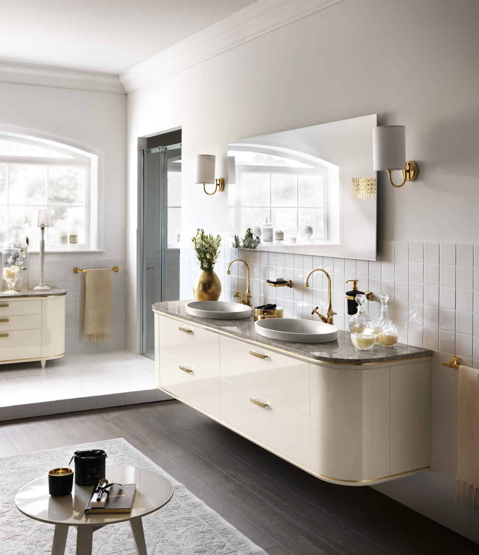 Elegant bathroom with double vanity sinks, gold fixtures, large mirror, and neutral decor.