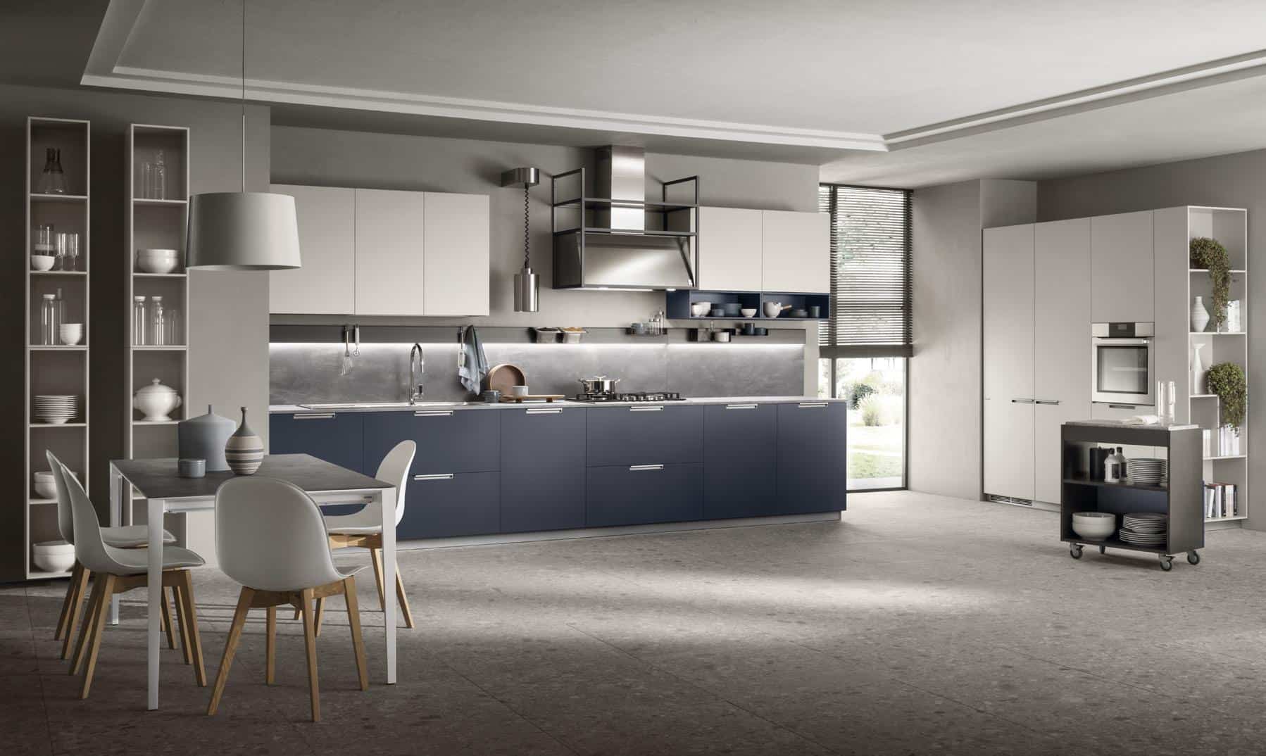 Modern kitchen with blue and white cabinetry, a dining table with four chairs, stainless steel appliances, and a rolling kitchen cart.