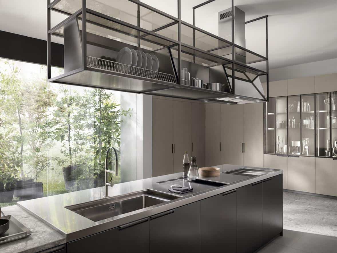 Modern kitchen with sleek countertops, a stainless steel sink, overhead metal shelving, large glass windows, and cabinetry.