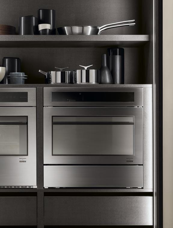 Modern kitchen with two built-in stainless steel ovens and shelves above holding cookware and jars.
