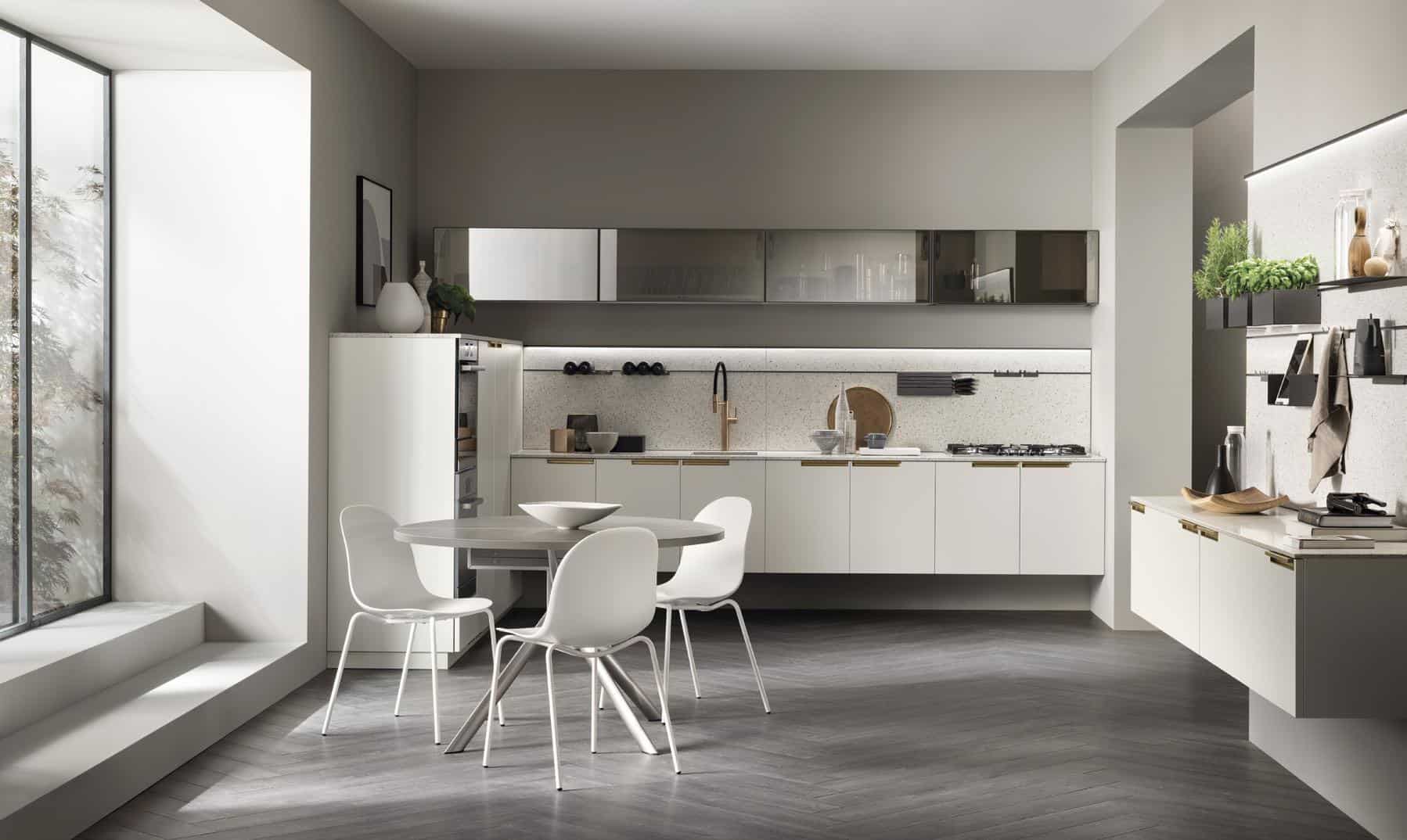 Modern kitchen with sleek cabinets, a round dining table with four white chairs, and large windows letting in natural light.