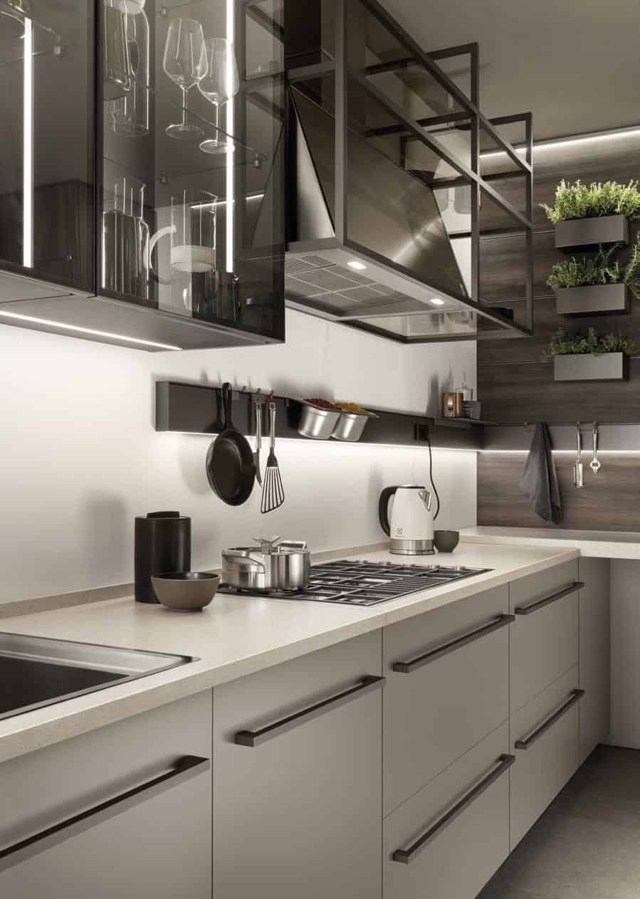 Modern kitchen with sleek cabinetry, a cooktop, kettle, utensils on a rail, and organized shelving.