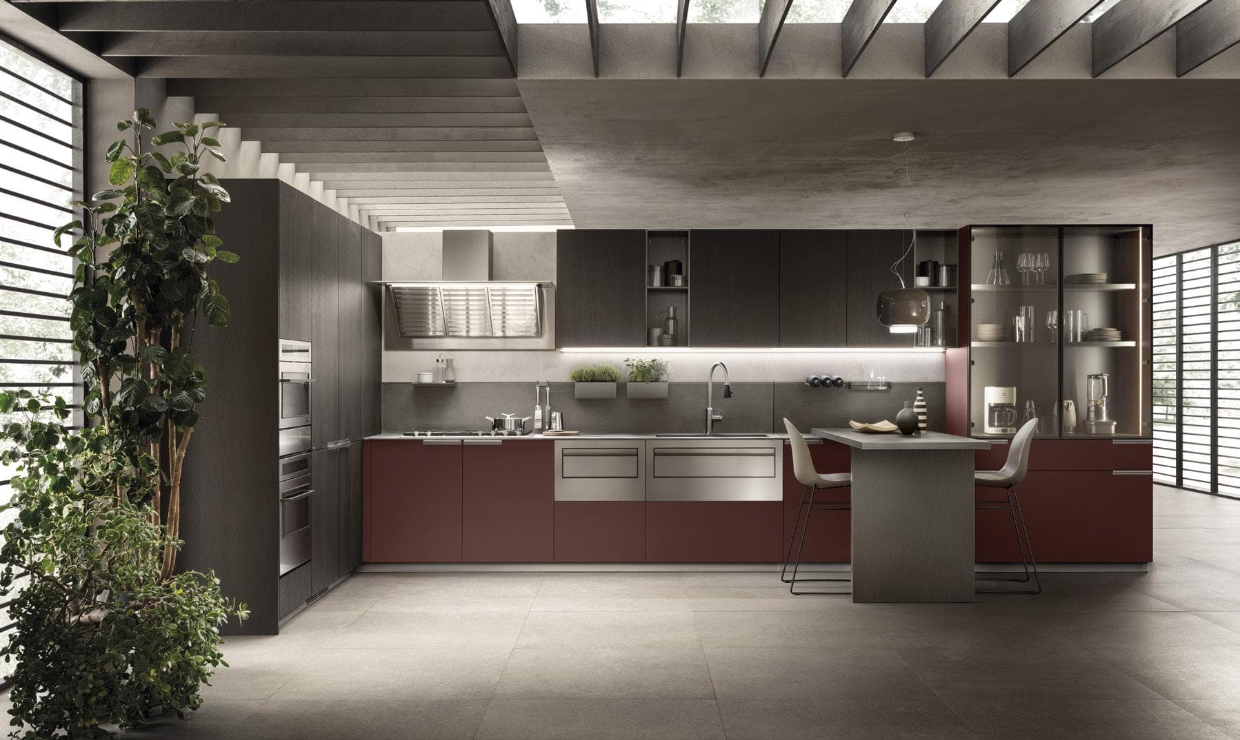 Modern kitchen interior with sleek brown and gray cabinetry, stainless steel appliances, and a large plant on the left. There is a central island with two chairs, and a glass cabinet displaying dishware. Skylights and large windows provide natural light.