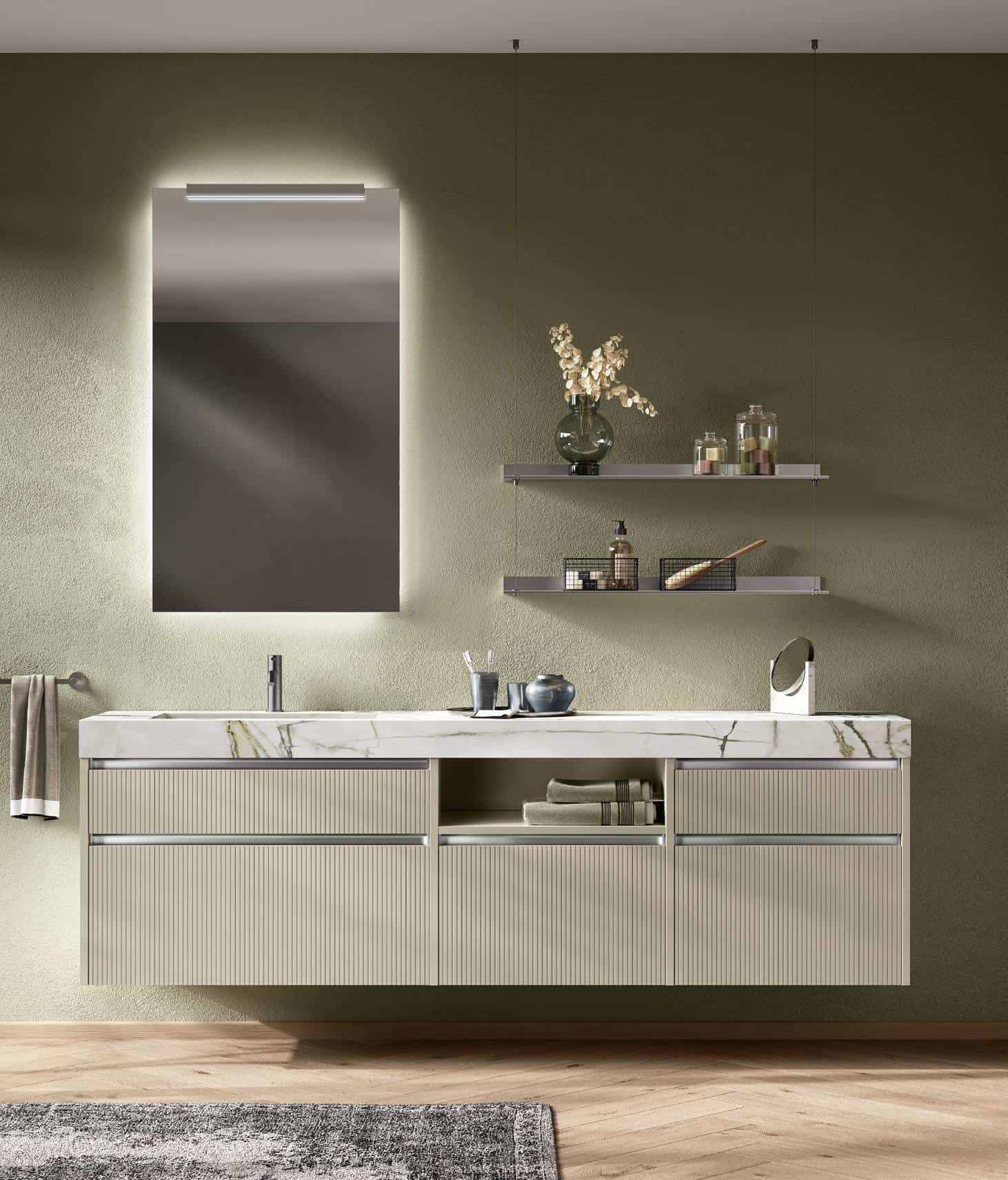 Modern bathroom with a wall-mounted vanity, marble countertop, illuminated mirror, and two floating shelves on a green wall.