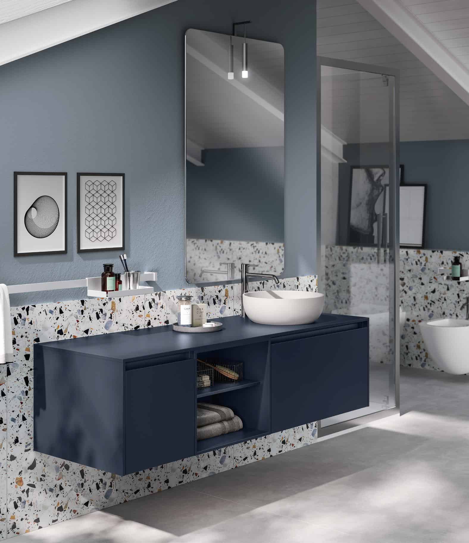 Modern bathroom with a blue floating vanity, terrazzo backsplash, large mirror, and minimalist decor under a sloped ceiling.