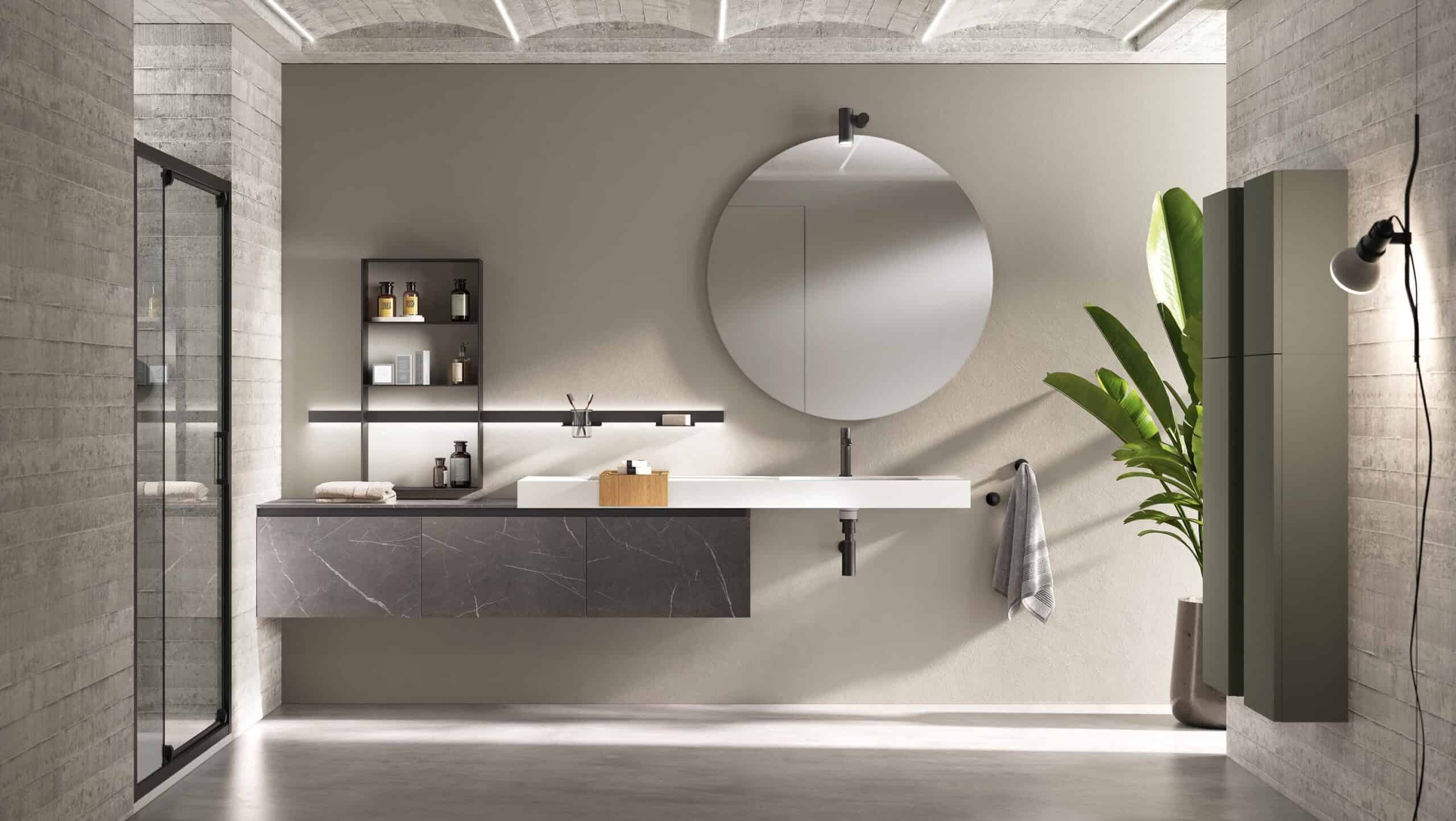 Modern bathroom with a round mirror, floating vanity, open shelving, a potted plant, and a glass shower door.