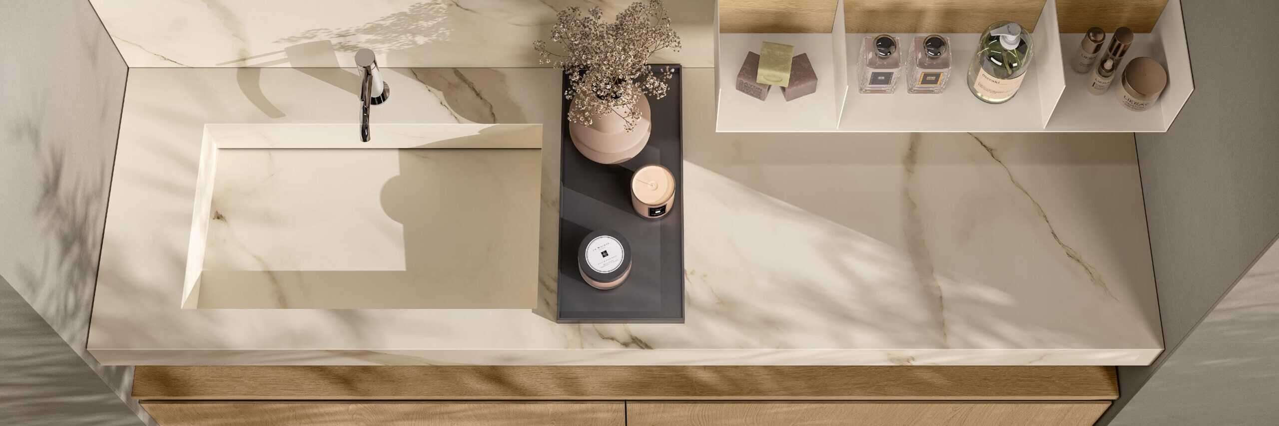 Marble bathroom countertop with integrated sink, faucet, decorative vase with dried flowers, and assorted toiletries on shelves.