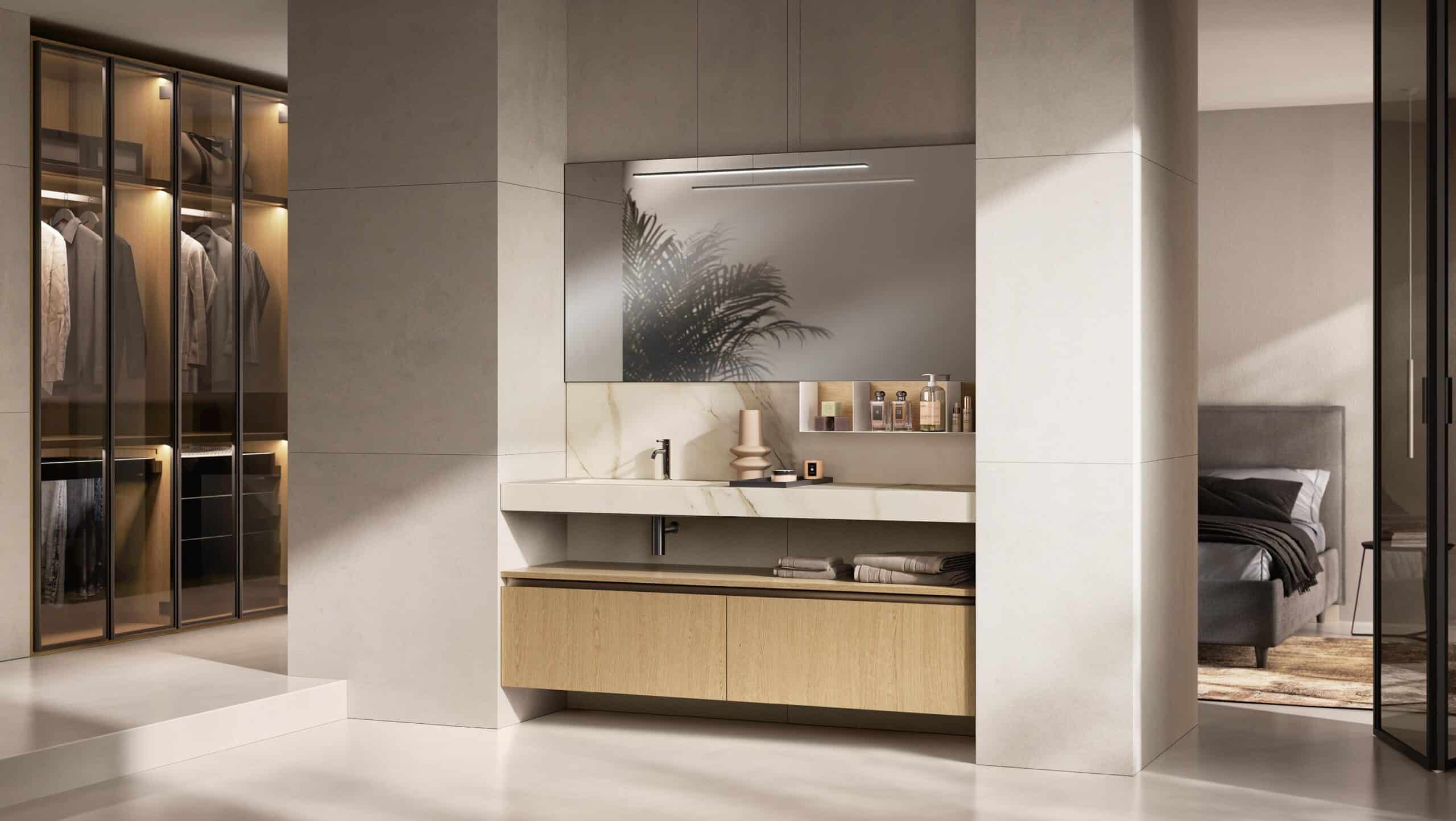 Modern bathroom with a marble sink and wooden cabinetry, adjacent to a walk-in closet with glass doors and a bedroom with a gray bed.