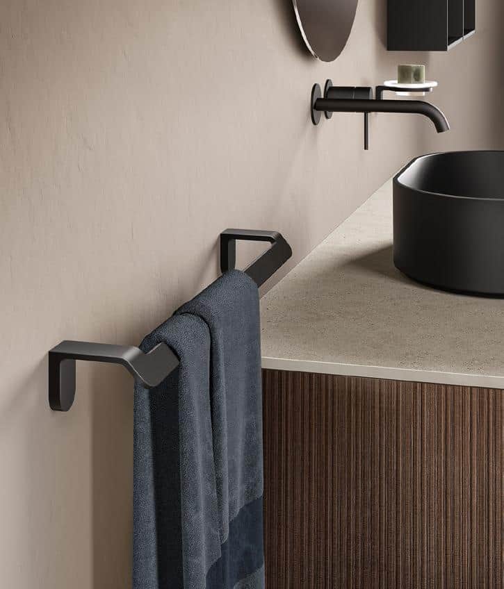 Modern bathroom with a dark round basin, wall-mounted faucet, round mirror, and a black towel rail with a dark towel.