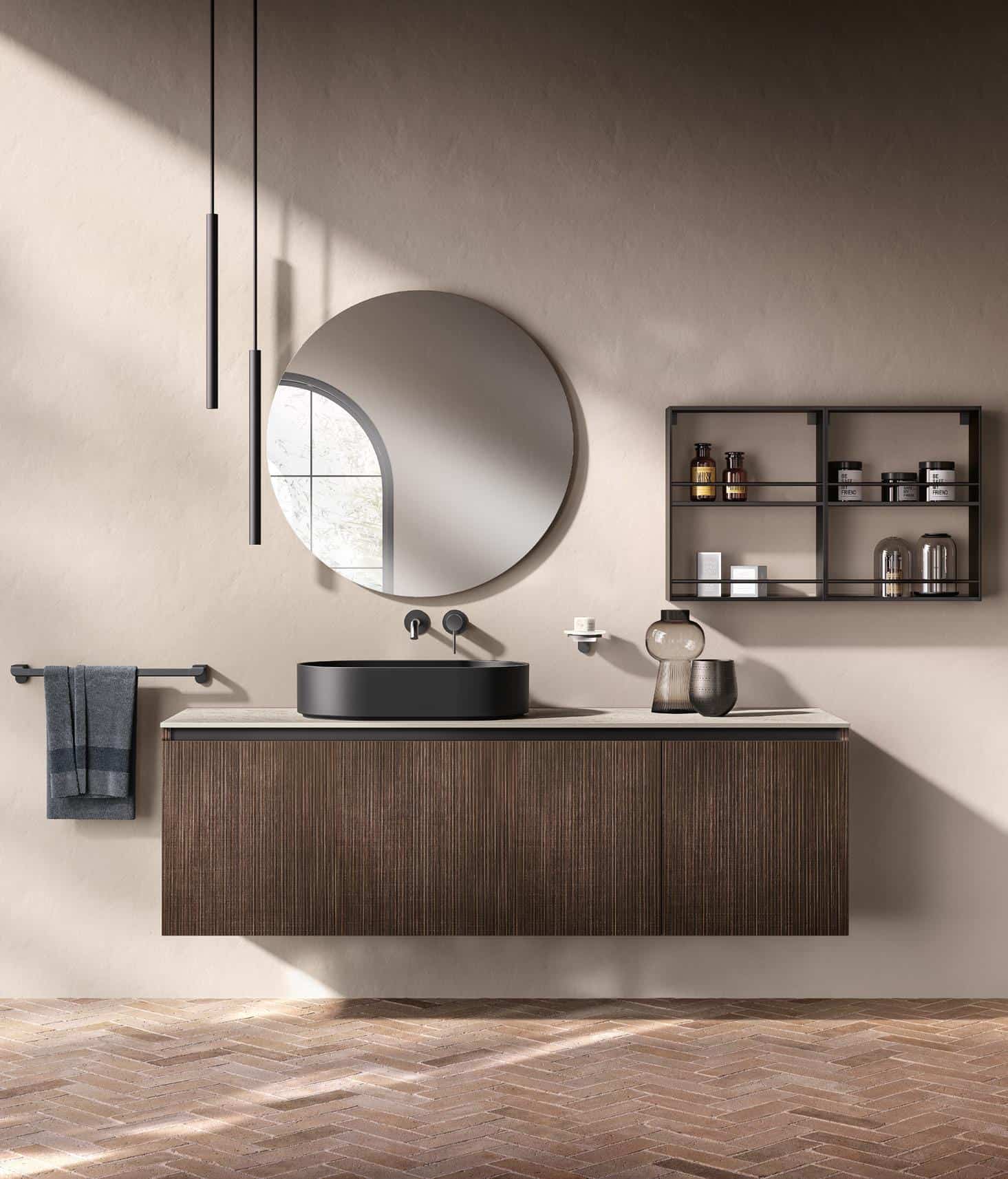 Modern bathroom with a wall-mounted wooden vanity, round mirror, black sink, and floating shelves holding toiletries.