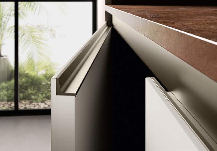 Close-up view of modern kitchen cabinets with handleless design and a view of a garden through a window in the background.