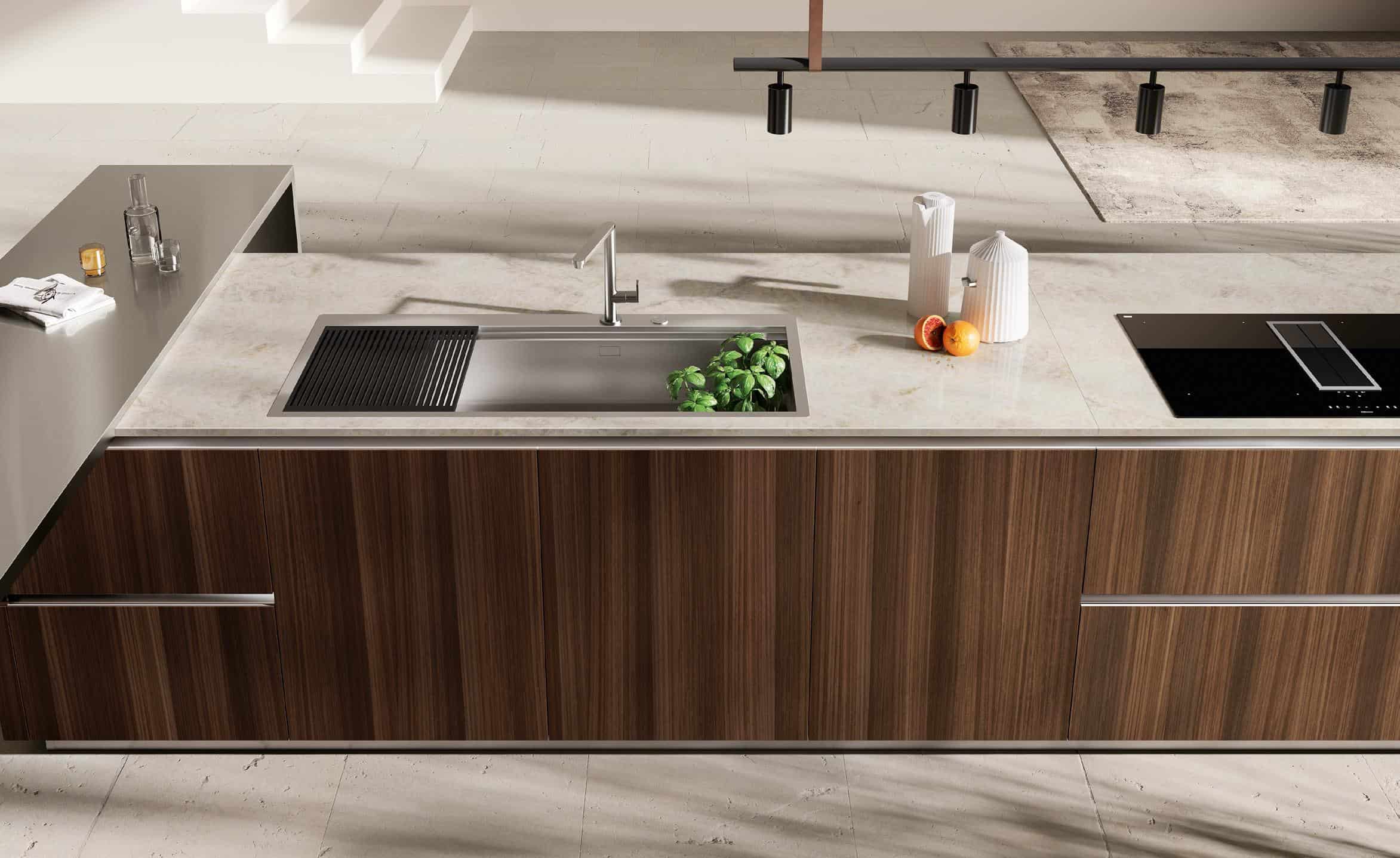 Modern kitchen countertop with a sink, faucet, potted plant, fruit, and kitchen appliances.