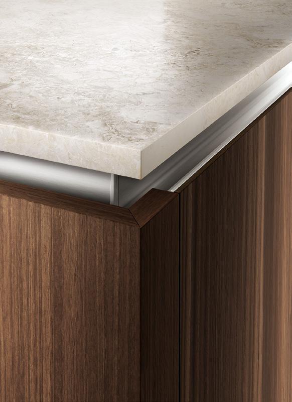 Close-up of a kitchen counter corner with a light stone countertop and dark wood cabinetry.