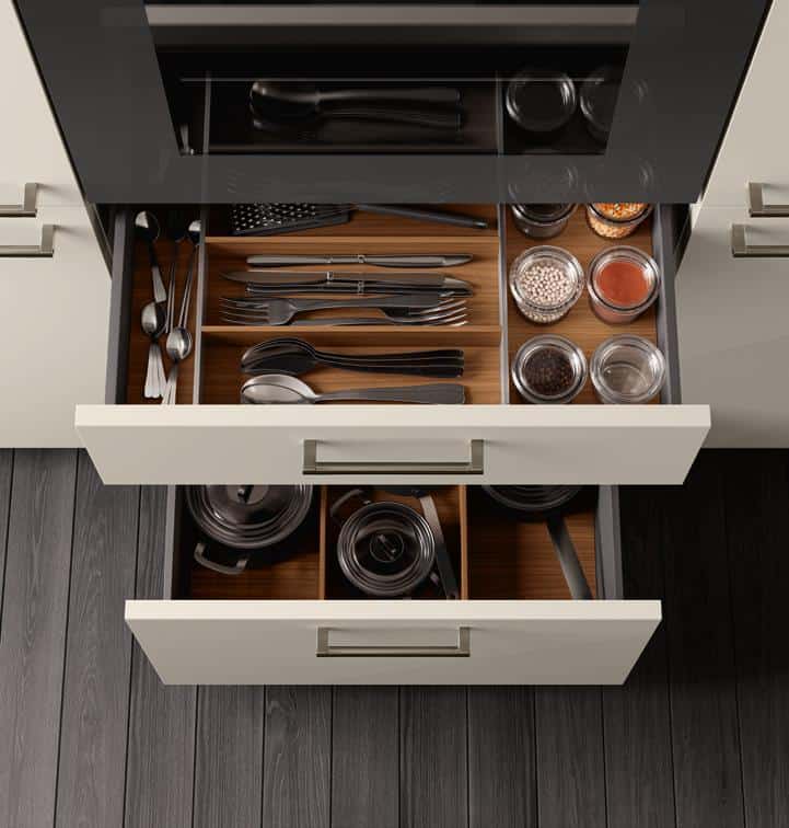 Open kitchen drawers with neatly organized cutlery, utensils, and spice jars.