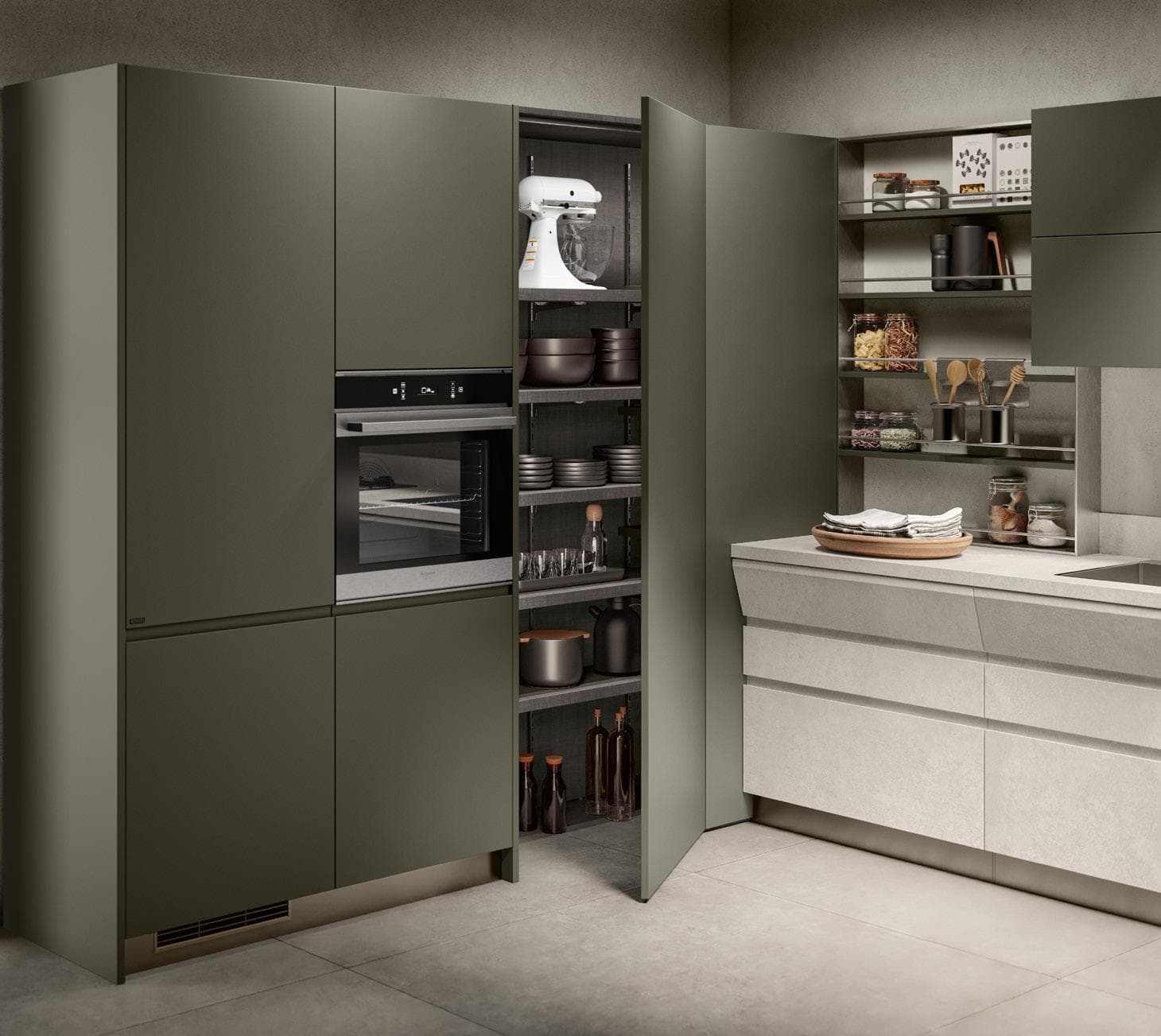 Modern kitchen with olive green cabinets, integrated oven, open pantry with cookware and mixer, shelves with jars, and a light gray countertop.