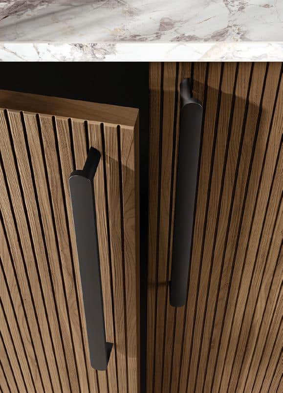 Wooden cabinet doors with vertical grooves and black metal handles, topped with a marble countertop.