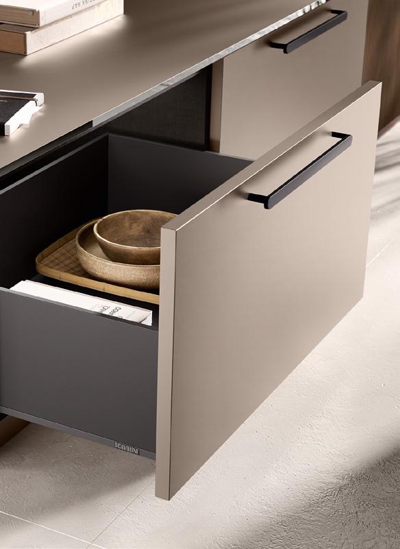 Open kitchen drawer with wooden bowls and trays inside, featuring a modern black handle.