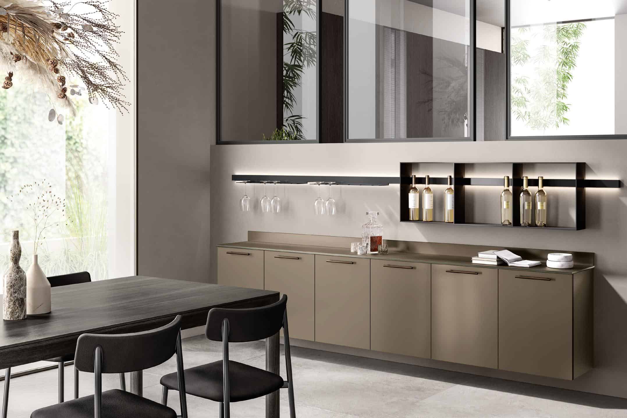 A modern kitchen interior with beige cabinets, a black table with chairs, hanging wine glasses, and bottles on a shelf.