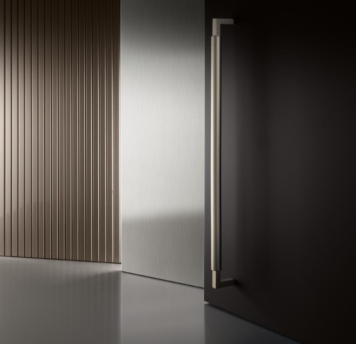 Modern interior with a sleek metal door handle, vertical paneling, and smooth reflective surfaces.