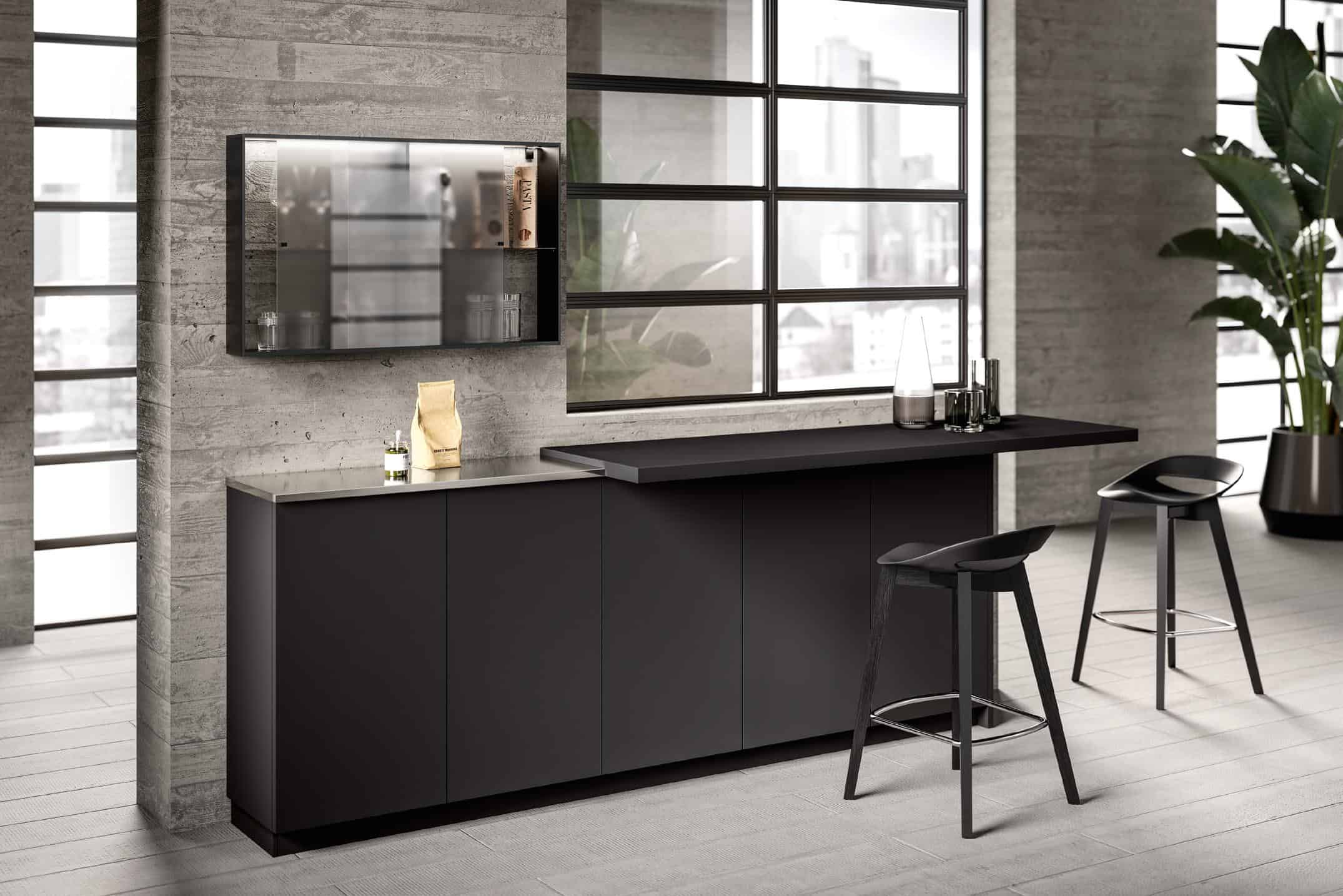 Modern kitchen interior with dark cabinets, a sleek countertop, two black bar stools, large windows, and a potted plant.