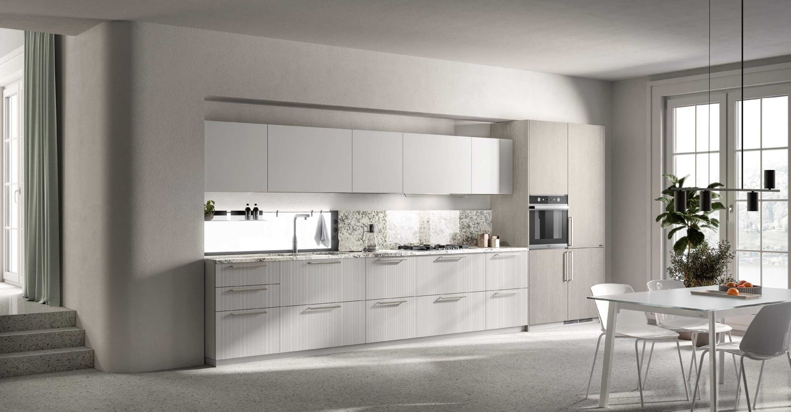 Modern kitchen with white cabinets, marble backsplash, built-in oven, and a sleek dining area with a glass table and white chairs. Pendant lights hang above the table, and large windows provide natural light.