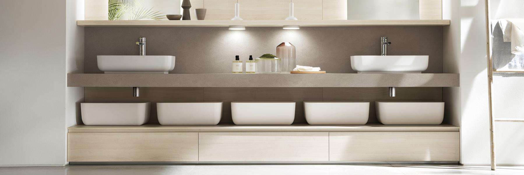 Modern bathroom with two vessel sinks, illuminated shelving, and storage compartments below.