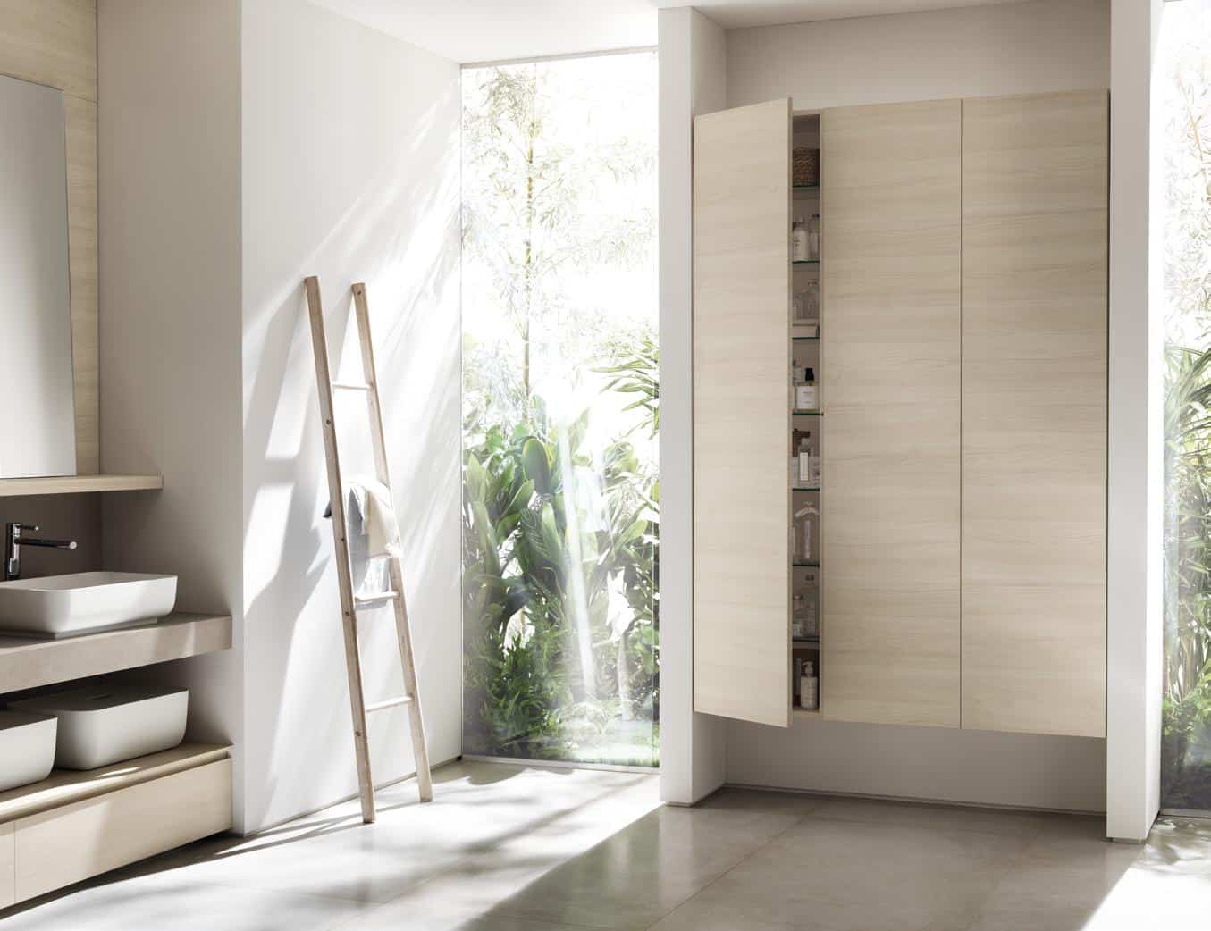 Modern bathroom interior with large mirrored cabinet, ladder with towel, sink, and large window with greenery outside.