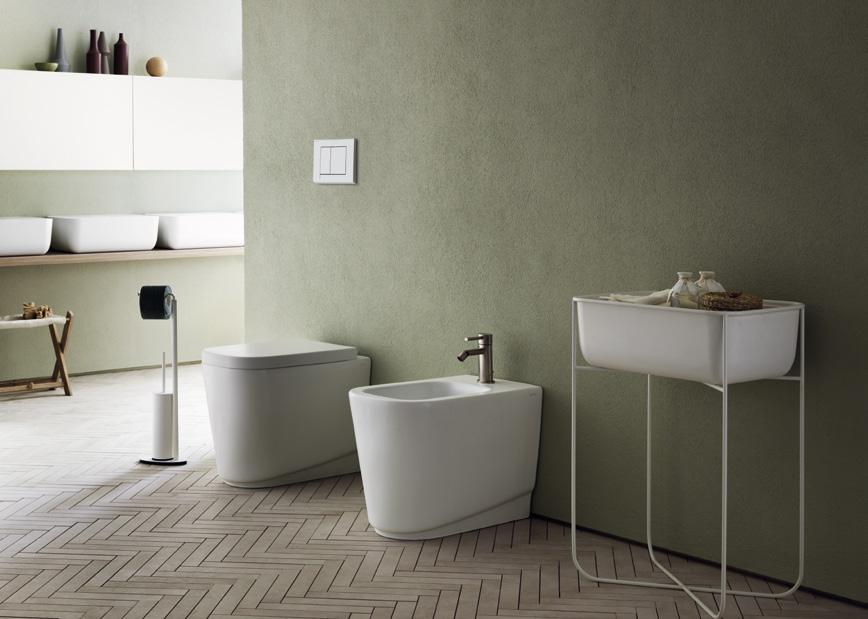 Modern bathroom with white fixtures, green walls, and herringbone tile floor.