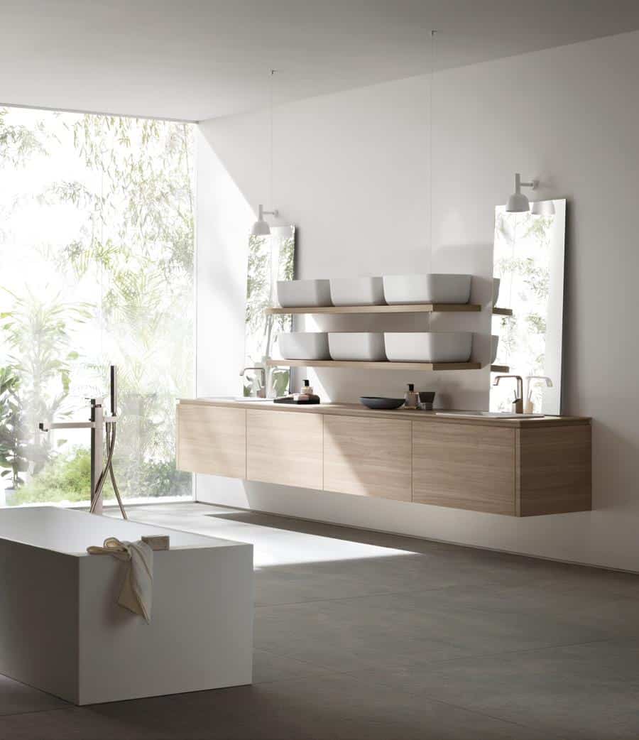 Minimalist bathroom with large windows, a floating wooden vanity, mirrors, and modern white fixtures.