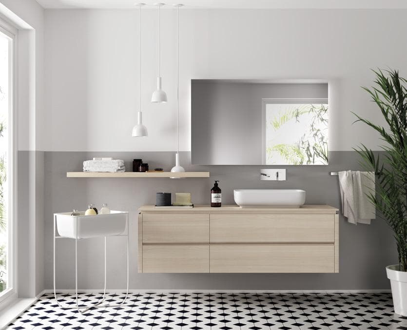 Modern bathroom with light wood vanity, white sink, large mirror, pendant lights, a potted plant, and geometric floor tiles.
