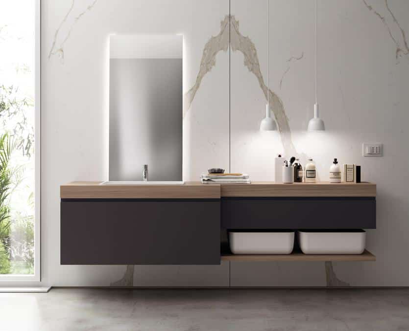 Modern bathroom vanity with a floating dark cabinet, wooden countertop, large backlit mirror, and pendant lights.