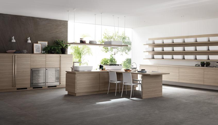 Modern kitchen with light wood cabinets, a central island with chairs, large windows, and open shelves.