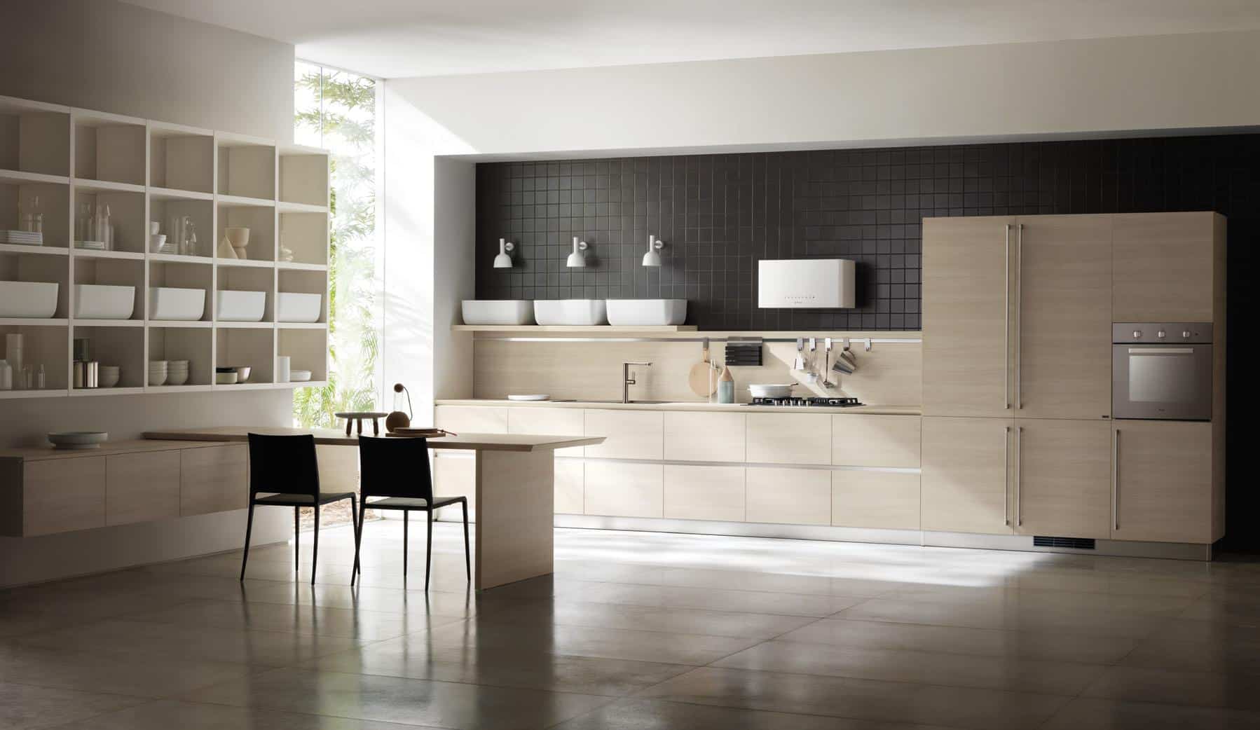 Modern kitchen with light wood cabinets, black tiled backsplash, stainless steel appliances, open shelving, and a dining area with two chairs.