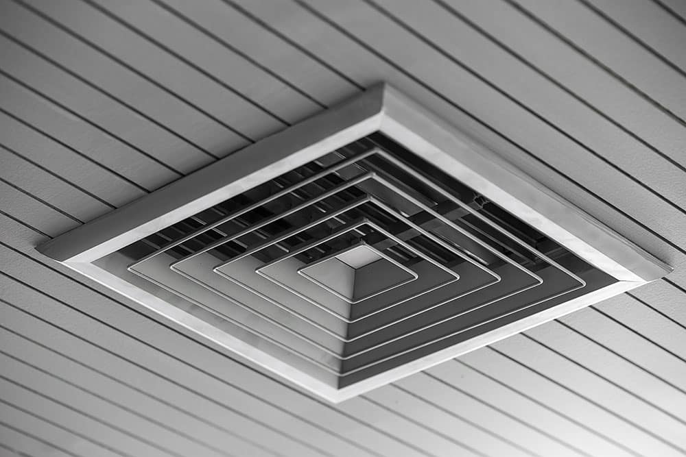 Square ceiling air vent with concentric grille design mounted on a slatted ceiling, ideal for ceiling installation in mini split HVAC systems.