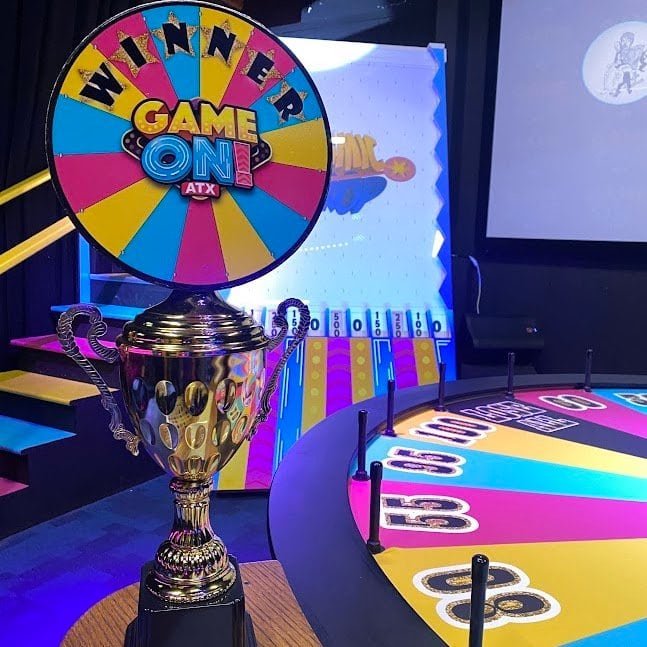 GameOn ATX winner's trophy, colorful wheel to spin, and Plinko-esque board.