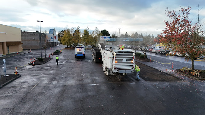 Workers from Legacy Paving improve a shopping center parking lot, making the surface smoother and safer for cars and people.