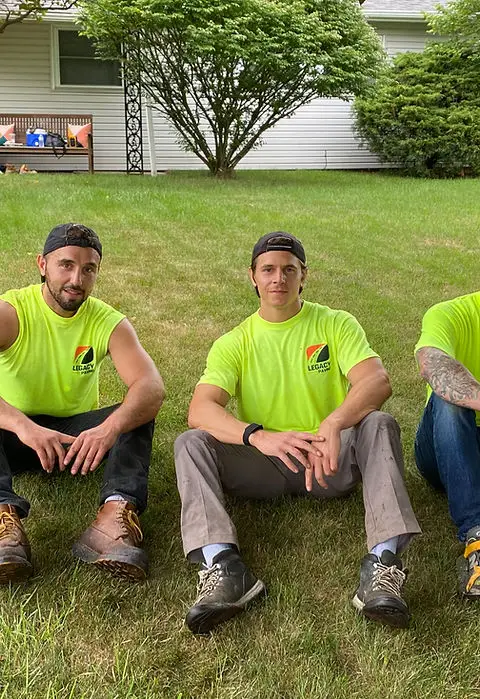 Three Legacy Paving workers rest together outdoors, showing pride in their teamwork and the quality of their work.