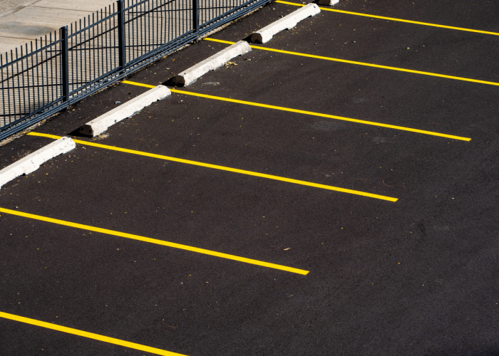A smooth, freshly paved parking lot made by Legacy Paving, showing organized spaces and secure wheel stops for safe parking.