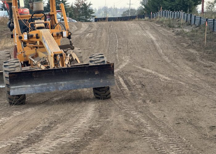 A Legacy Paving grader smooths a road, showing how the company improves roads for safer, better travel.