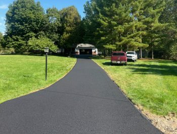 A neat blacktop driveway by Legacy Paving shows a well-done job, making the home look tidy and inviting with easy parking.