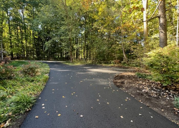 A smooth new driveway by Legacy Paving shows quality work and lasts through changing seasons in a peaceful, leafy area.