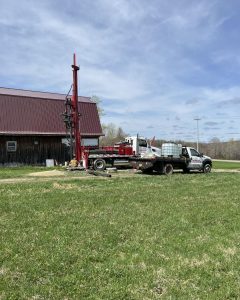 Equipment from McCandless Well Drilling and Services Inc. ready for water well drilling work on a farm in the countryside.