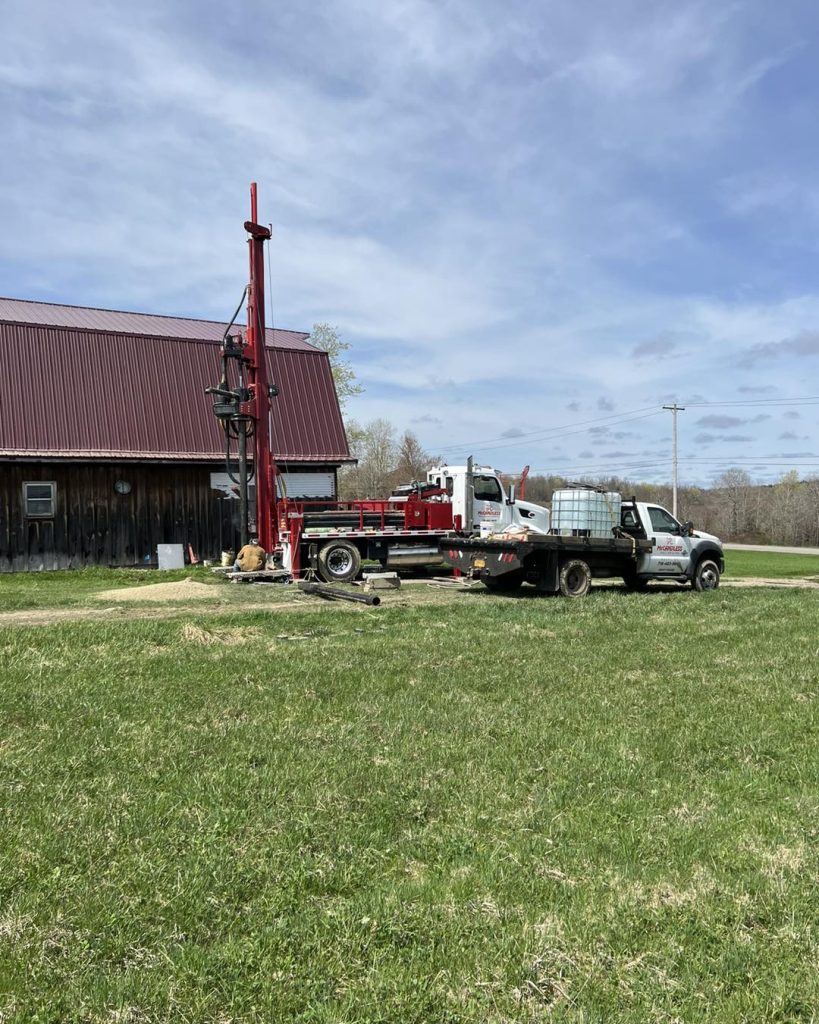 Equipment from McCandless Well Drilling and Services Inc. ready for water well drilling work on a farm in the countryside.
