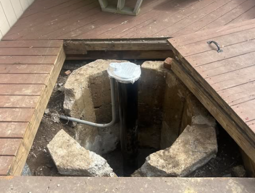 A deck shows a hole with pipes beneath it, suggesting McCandless Well Drilling fixed or serviced a water well nearby.