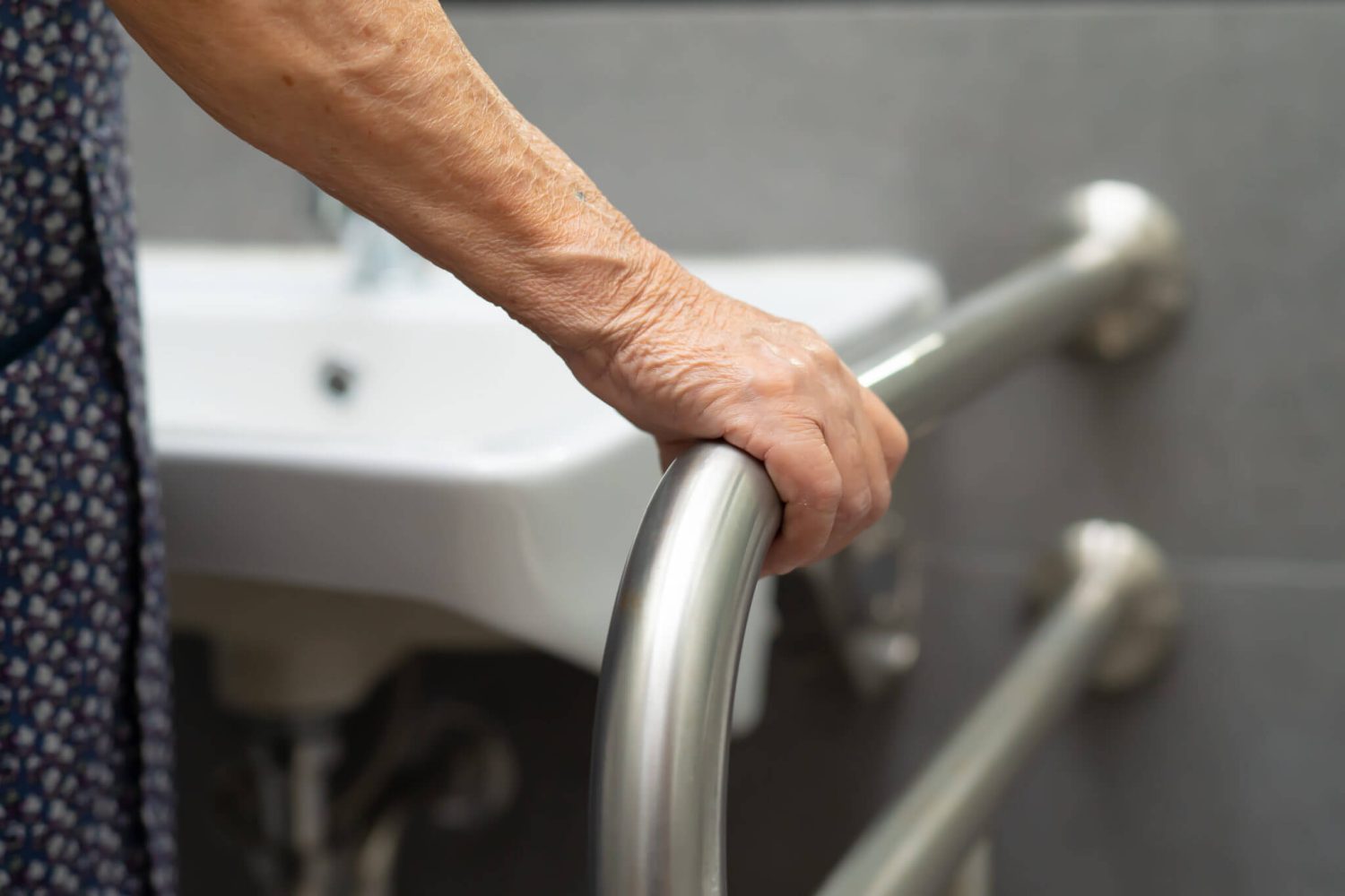 A person is safely holding a grab bar in a bathroom, showing how Mid State Baths helps make bathrooms safer for seniors.