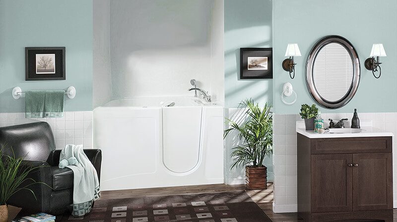 A walk-in bathtub and cozy furniture show a safe, relaxing bathroom designed by Mid State Baths in Harrisburg, PA.
