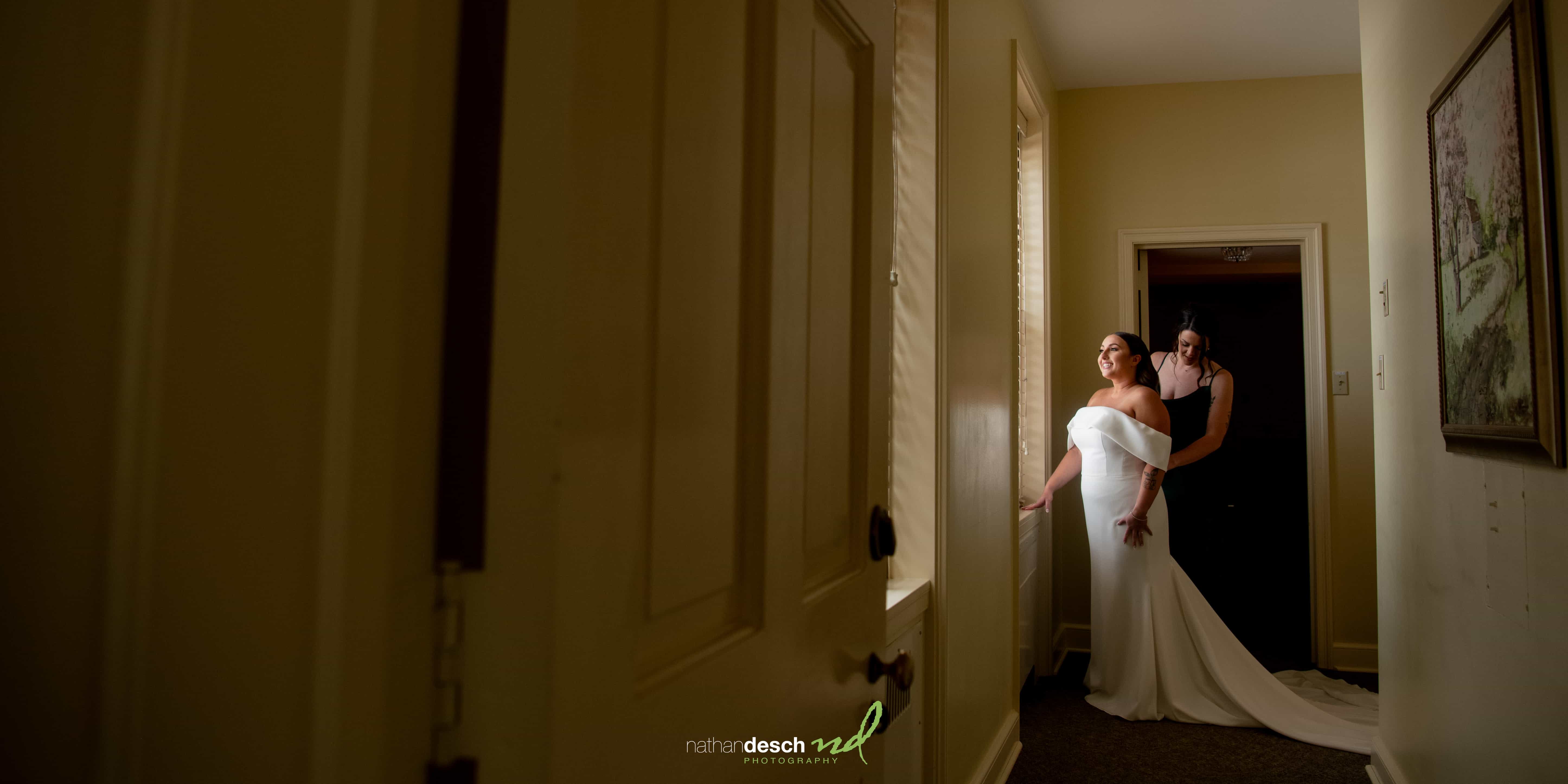Bride getting dressed by window