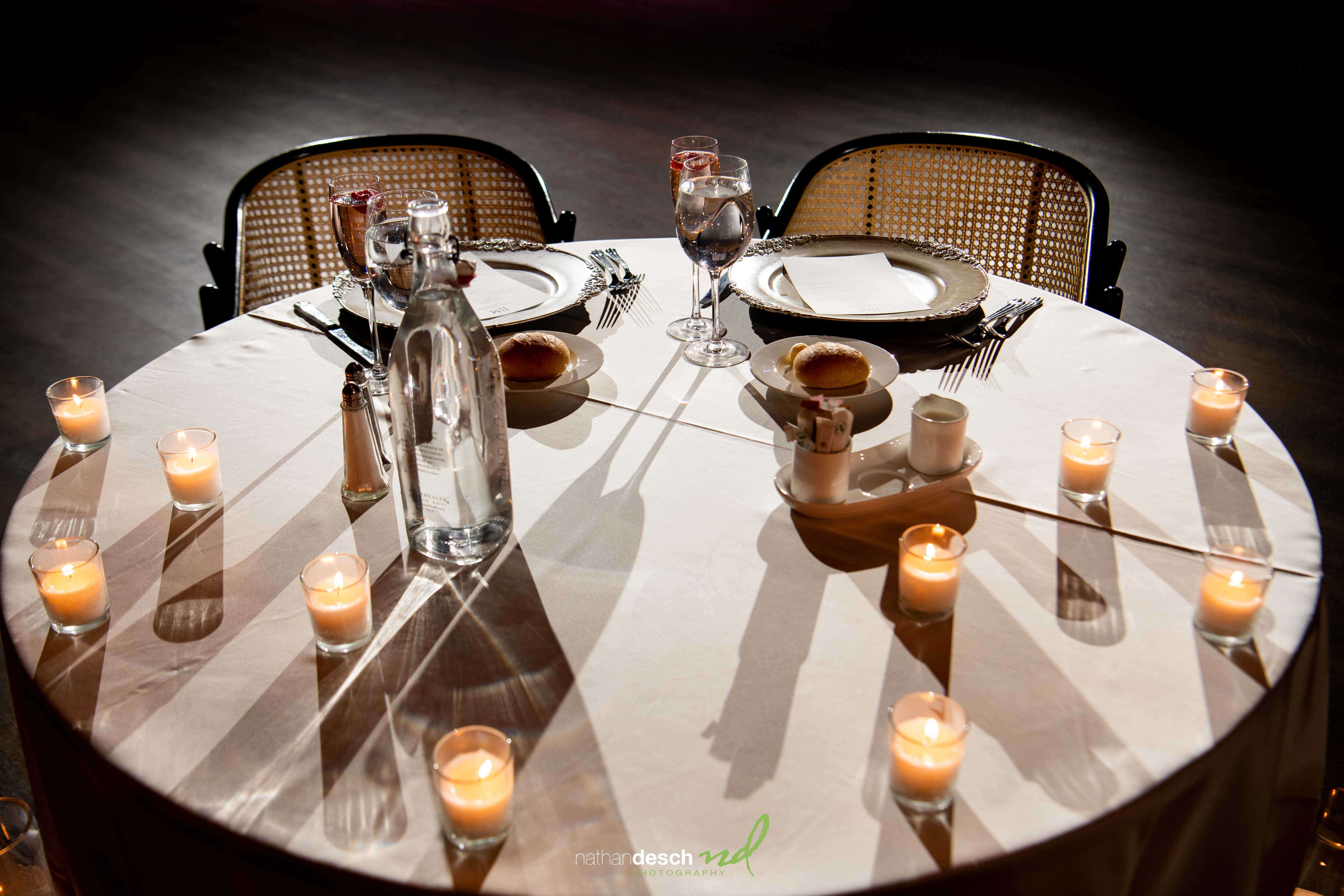 Romantic spring wedding table for two with candles, bread rolls, and elegant place settings at Tendenza reception venue.