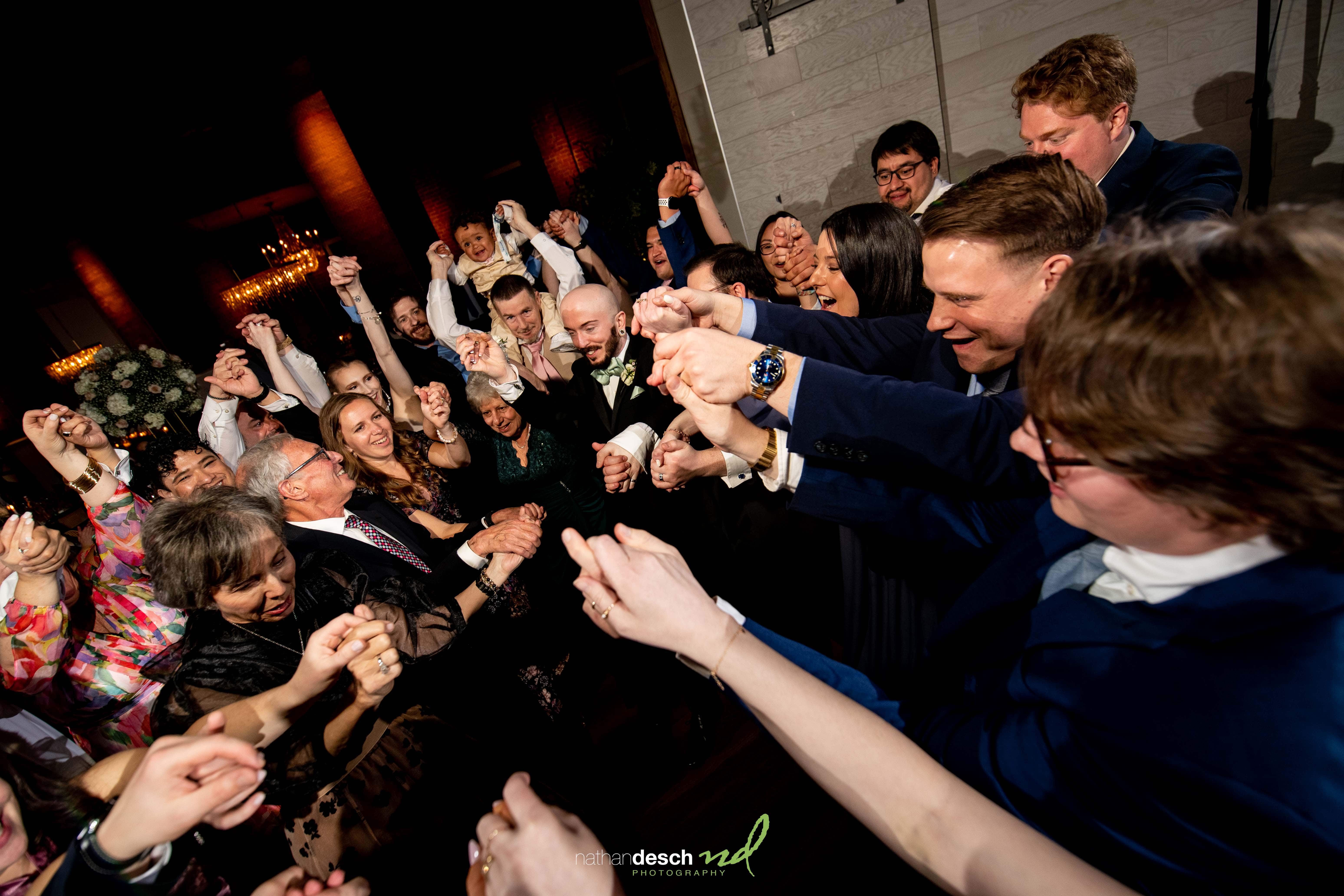 Guests in elegant attire joyfully dancing and celebrating at a vibrant spring wedding reception at Tendenza ballroom.