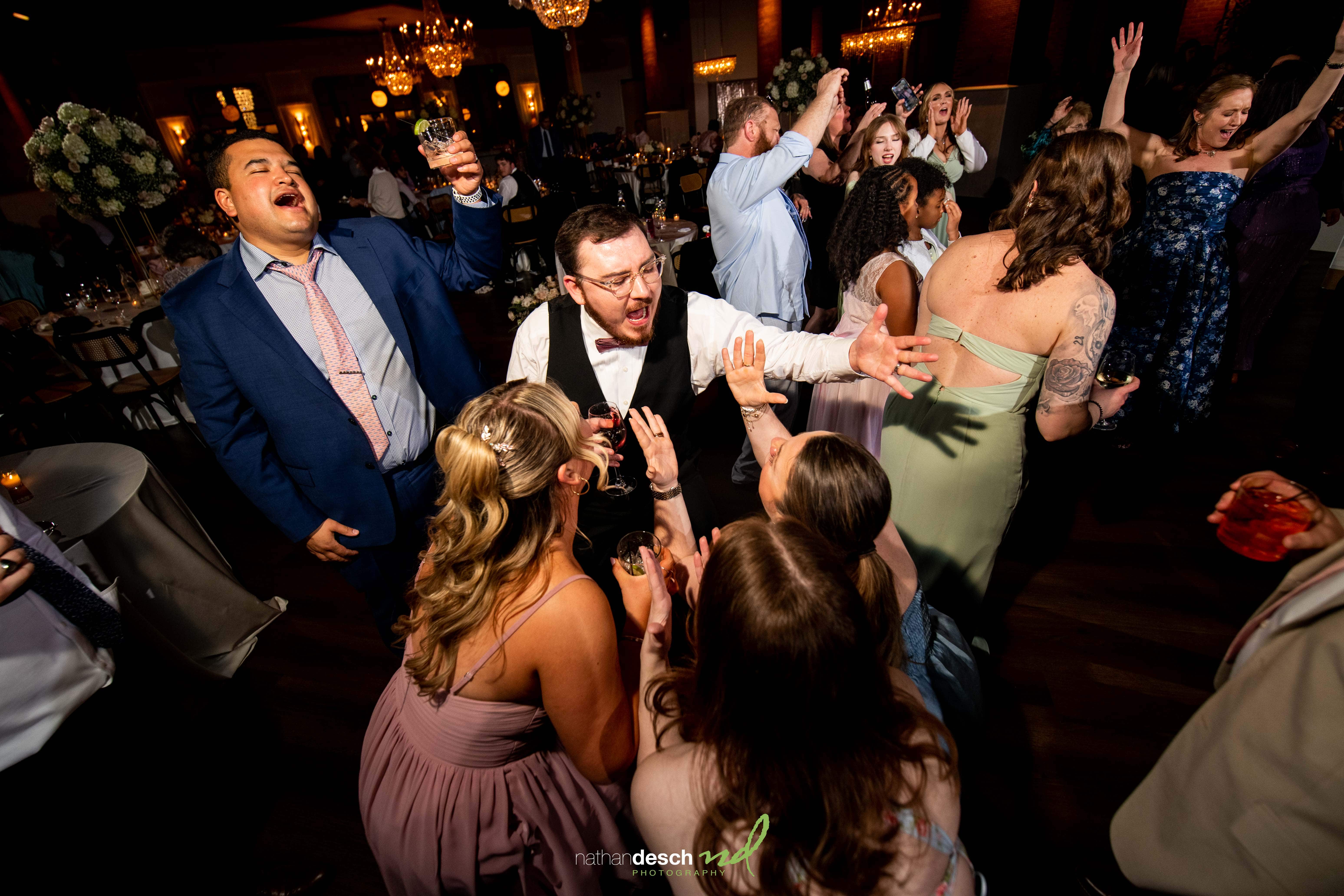 Guests in formal wear joyfully dancing and celebrating at a vibrant spring wedding reception at Tendenza.